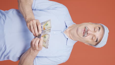 Vertical-video-of-Old-man-counting-money-looking-at-camera.